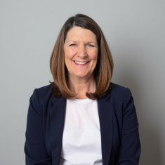 Headshot of smiling woman wearing a white shirt and black blazer